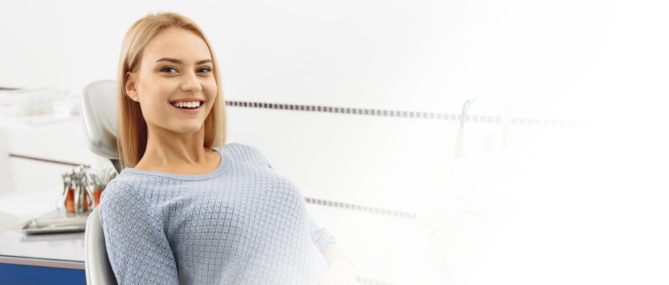 Woman in gray sweater smiling in treatment chair in periodontal office in Vista