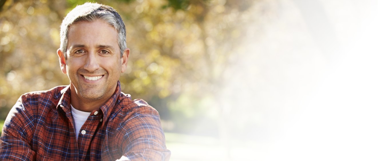 Man in red plaid shirt smiling outdoors with All on 4 dental implants