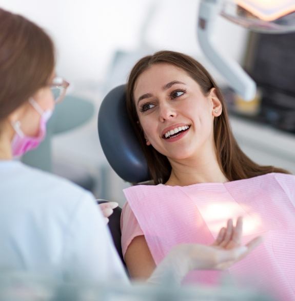 Woman in dental chair talking to dental team member