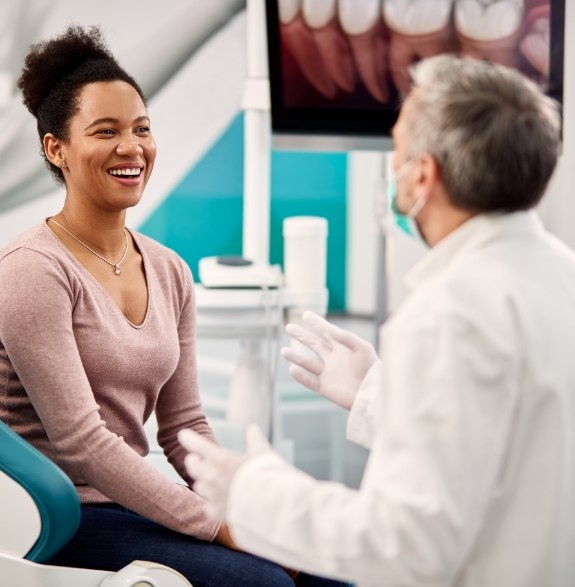 Woman in dental chair smiling at her dentist