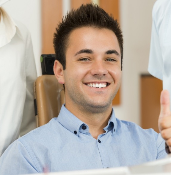 Man smiling and giving thumbs up in dental chair