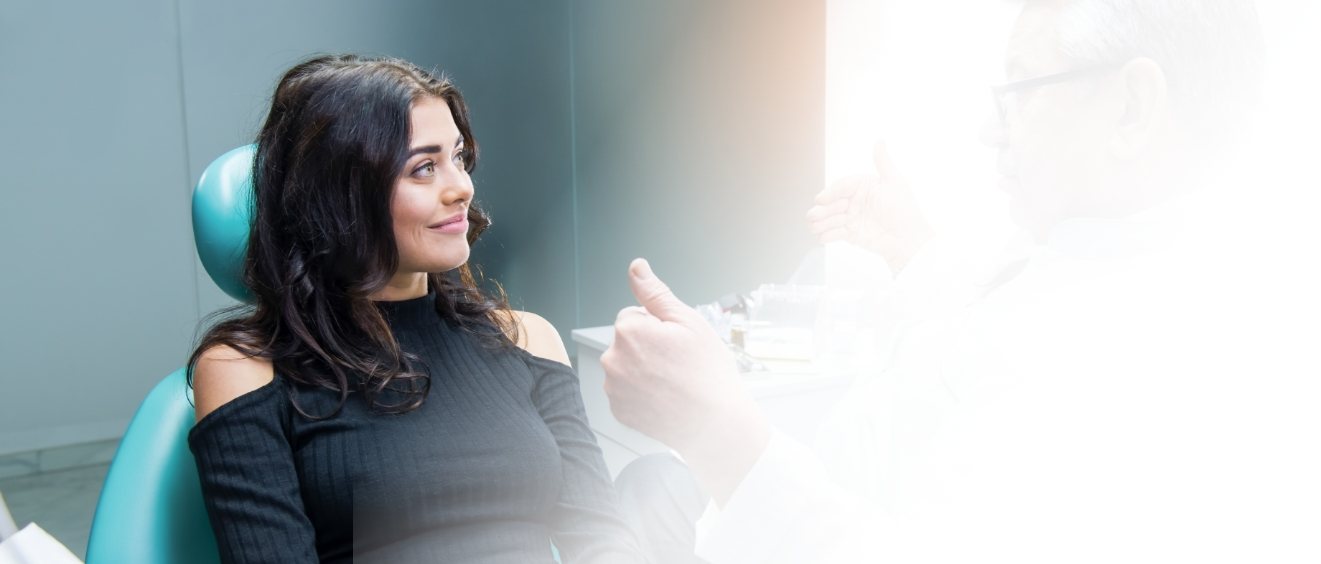 Woman in dental chair listening to her dentist