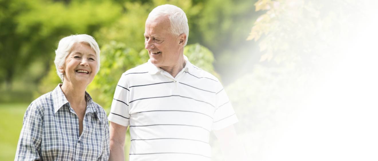 Senior man and woman walking outdoors and smiling with implant dentures in Vista