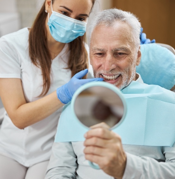 Senior dental patient looking at his smile in a mirror