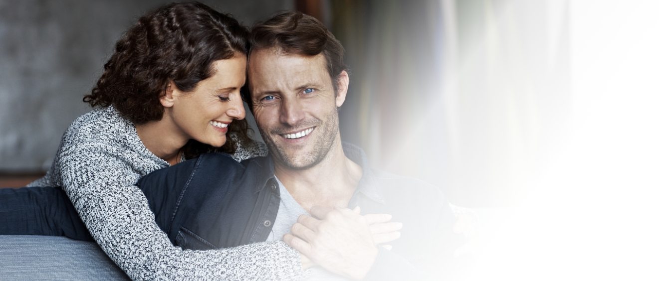 Man and woman sitting on couch and hugging