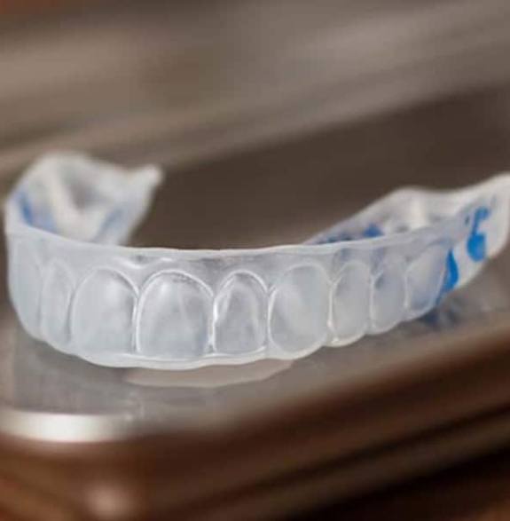 Clear mouthguard resting on a metal tray