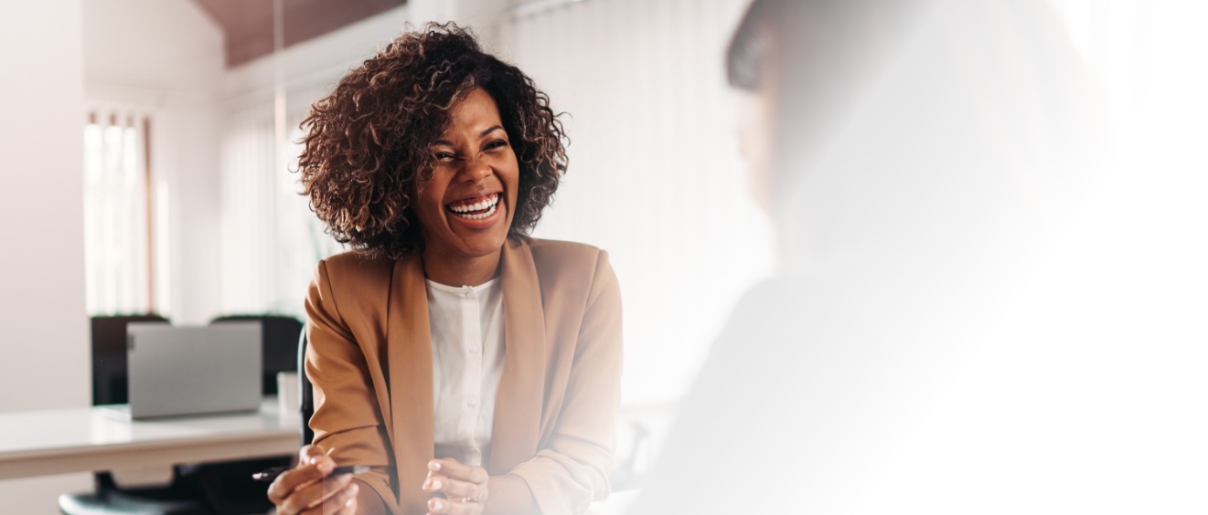 Woman laughing with person sitting across table