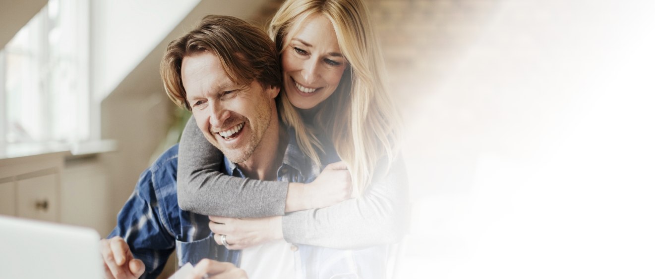 Woman hugging man looking at laptop for periodontist reviews