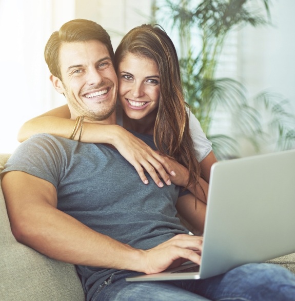 Smiling man and woman on couch with laptop