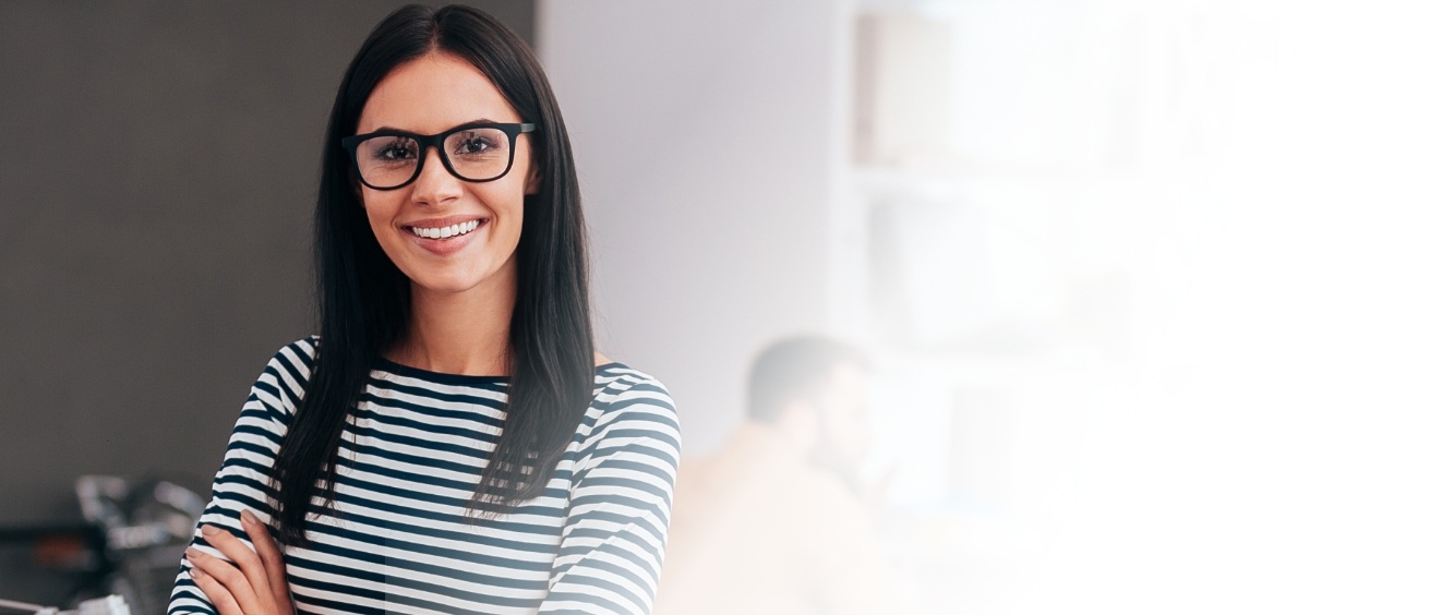 Woman in black and white striped blouse smiling with her arms crossed